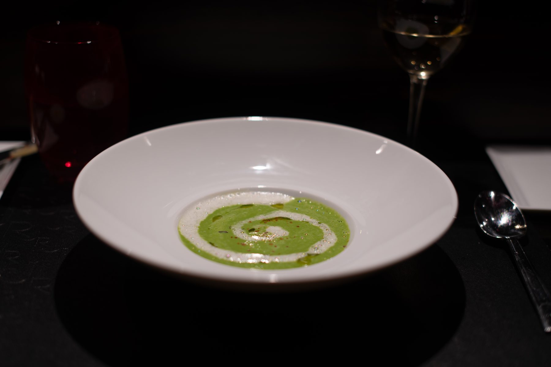 Green velouté swirl on a white plate · Paris
